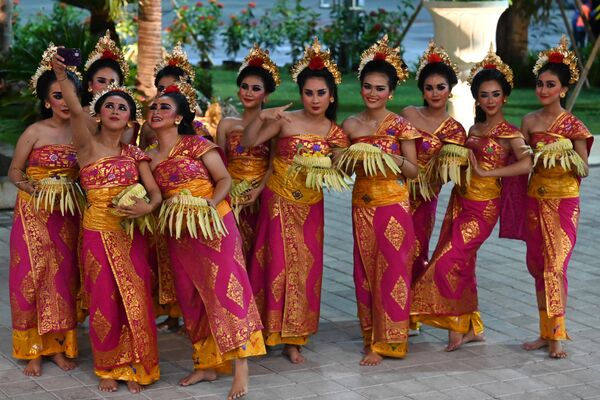 Các vũ công Bali mặc trang phục truyền thống chụp ảnh tự sướng khi đợi các nhà lãnh đạo G20 đến sân bay quốc tế ở Tuban, Bali. - Sputnik Việt Nam