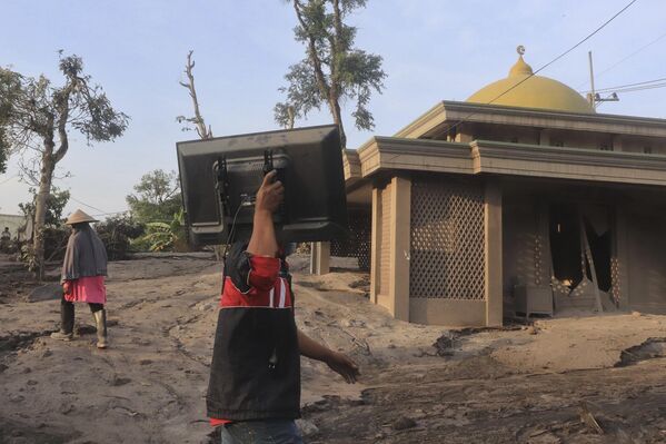 Cư dân của làng Kadzhar Kuning trẹn đảo Java ở Indonesia dọn dẹp những thứ còn sót lại từ ngôi nhà bị hư hại do núi lửa Semeru phun trào - Sputnik Việt Nam