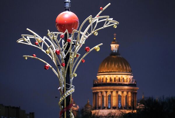 Một cột đèn trang trí Giáng sinh trên đường phố St. Petersburg. Phía sau là Nhà thờ St. Isaac. - Sputnik Việt Nam