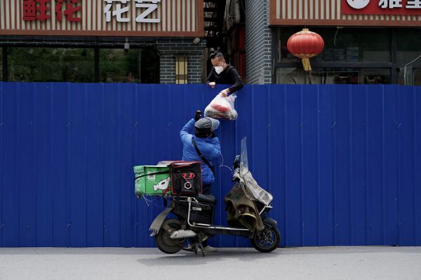 Nhân viên chuyển phát nhanh giao thực phẩm cho cư dân ở khu vực cách ly ở Bắc Kinh. - Sputnik Việt Nam
