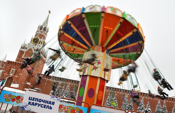 Du kháchtham dự hội chợ GUM đang trượt vòng quay ngựa gỗ trên Quảng trường Đỏ ở Moscow. - Sputnik Việt Nam