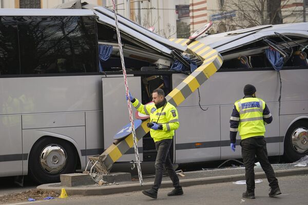 Cảnh sát đứng cạnh chiếc xe buýt chở 47 công dân Hy Lạp đâm vào thanh hạn chế chiều cao ở lối vào đường hầm ở Bucharest, Romania, khiến 1 người thiệt mạng, ngày 23 tháng 12 năm 2022, Romania. - Sputnik Việt Nam