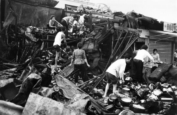 Người dân thu dọn đồ đạc trong đống đổ nát của các cửa hàng vào tháng 3 năm 1969 sau các cuộc tấn công bằng pháo cối của du kích vào chợ trung tâm Sài Gòn. - Sputnik Việt Nam