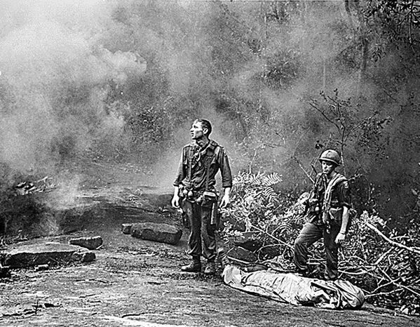 Lính Mỹ đứng bên đồng đội đãchếtkhiđợi máy bay trực thăng đến sơ tán khỏi khu rừng gần tỉnh Long Khánh, Việt Nam Cộng hòa, năm 1966. - Sputnik Việt Nam