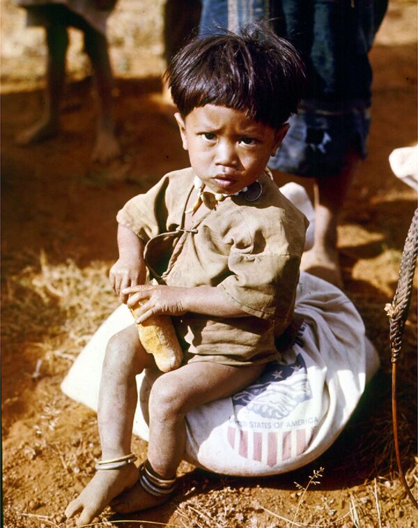 Cậu bé ngồi ăn trên bao tải lương thực của Mỹ, Chiến tranh Việt Nam, 1962. - Sputnik Việt Nam