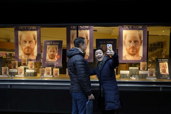 Cặp đôi chụp ảnh trước hiệu sách trưng bày sách &quot;Spare&quot; của Hoàng tử Harry ở London. - Sputnik Việt Nam
