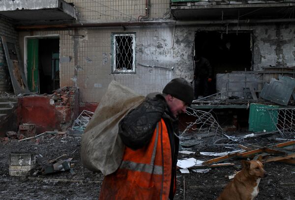 Người đàn ông dọn rác khỏi khu vực ngôi nhà bị hư hại do pháo kích ban đêm ở Gorlovka. - Sputnik Việt Nam