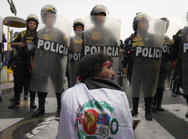 Người đàn ông ngồi trước hàng cảnh sát trong cuộc tuần hành chống Tổng thống Peru Dina Boluarte ở Lima, Peru. - Sputnik Việt Nam