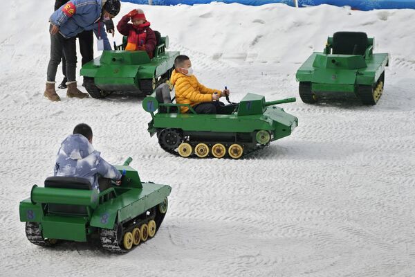 Trẻ em lái xe tăng đồ chơi trên tuyết tại công viên ở Bắc Kinh. - Sputnik Việt Nam