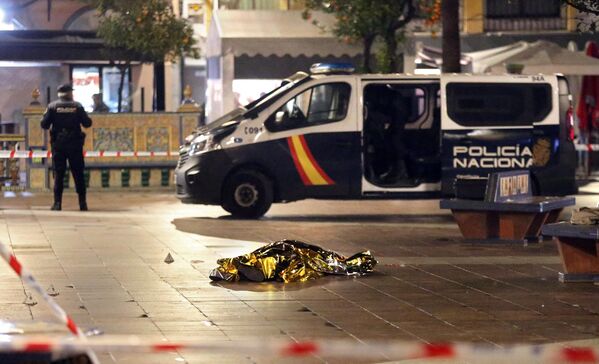 Thi thể của một người đàn ông nằm trên mặt đất, trong khi cảnh sát bảo vệ một khu vực ở Algeciras, Tây Ban Nha. - Sputnik Việt Nam