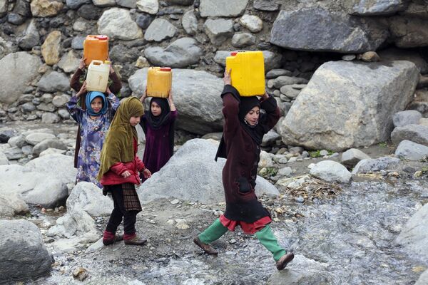Trẻ em mang những lon nước uống sau khi được đổ đầy từ một con suối ở huyện Dara-e-Noor, tỉnh Nangarhar, Afghanistan. - Sputnik Việt Nam