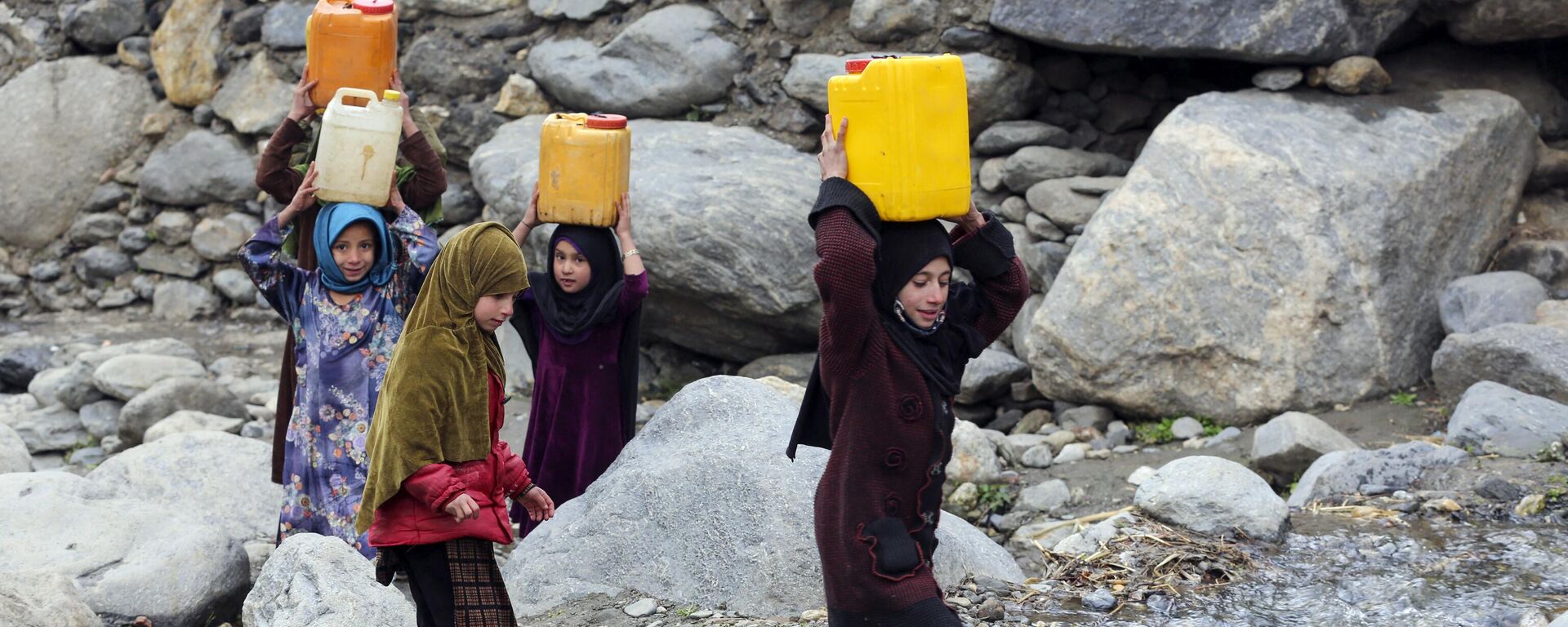 Trẻ em mang những lon nước uống sau khi được đổ đầy từ một con suối ở huyện Dara-e-Noor, tỉnh Nangarhar, Afghanistan. - Sputnik Việt Nam, 1920, 09.02.2023