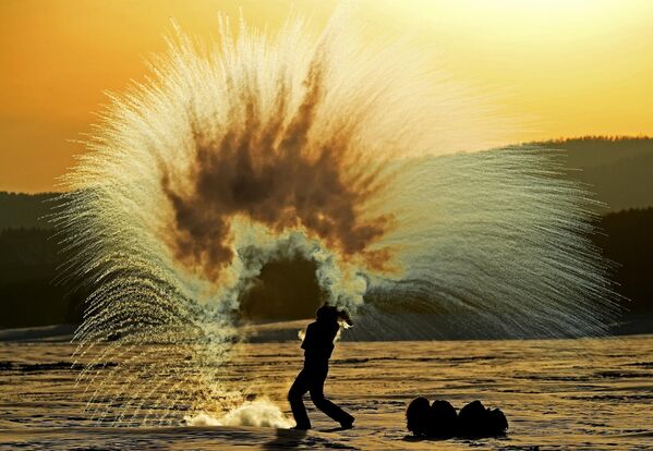 Cô gái đốt &quot;pháo hoa băng giá&quot; bằng cách ném nước nóng lên không trung, nước đóng băng khi đang bay do sương giá, trong hoàng hôn trên băng của hồ chứa Krasnoyarsk ở nhiệt độ không khí -36 độ C. - Sputnik Việt Nam