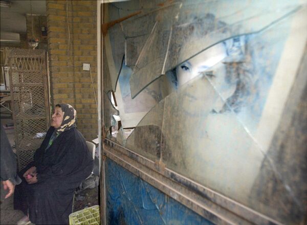 Chủ cửa hàng ngồi thẫn thờ nhìn cửa hàng bị hư hại sau cuộc ném bom vào ban đêm của Quân đội Mỹ, Iraq. - Sputnik Việt Nam