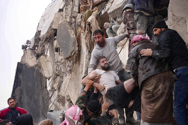 Cư dân giải cứungười đàn ông bị thương sau trận động đất ở thành phố Jandaris, Syria. - Sputnik Việt Nam