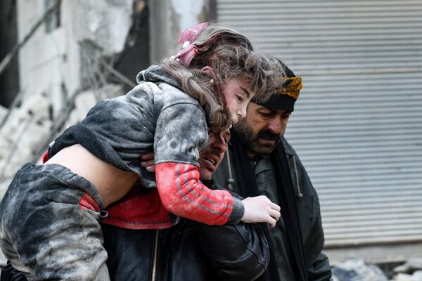 Người dân đưa đứa trẻ bị thương ra khỏi đống đổ nát của tòa nhà sập sau trận động đất ở thành phố Jandaris, tây bắc Syria. - Sputnik Việt Nam