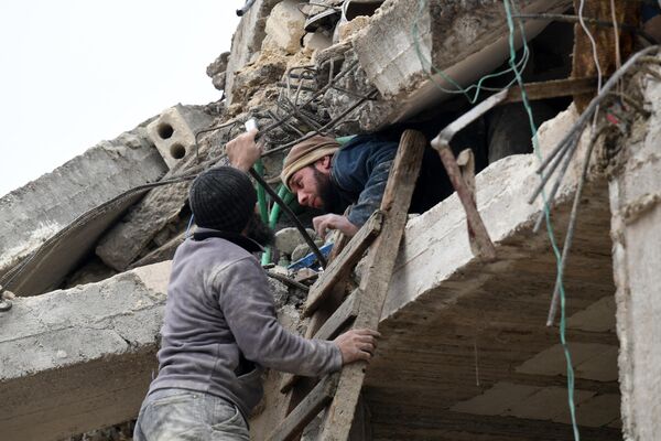 Người dân giúp người đàn ông bị thương thoát khỏi đống đổ nát của tòa nhà bị sập sau trận động đất ở thành phố Jandaris, tây bắc Syria. - Sputnik Việt Nam