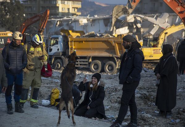 Phụ nữ chơi với con chó của mình khi lực lượng cứu hộ tiếp tục tìm kiếm nạn nhân trận động đất ở Antakya, Thổ Nhĩ Kỳ. - Sputnik Việt Nam
