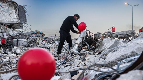 Ogun Sever Our, 38 tuổi, treo quả bóng bay trên đống đổ nát tòa nhà bị sập ở Antakya, miền nam Thổ Nhĩ Kỳ. - Sputnik Việt Nam
