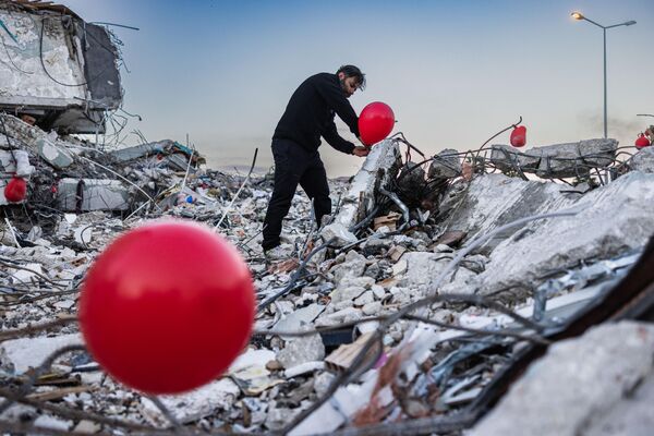 Ogun Sever Okur, 38 tuổi, treo quả bóng bay trên đống đổ nát tòa nhà bị sập ở Antakya, miền nam Thổ Nhĩ Kỳ. - Sputnik Việt Nam