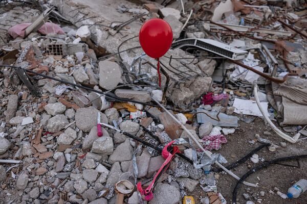 Những quả bóng bay màu đỏ treo trên đống đổ nát những tòa nhà bị sập như biểu tượng của &quot;đồ chơi cuối cùng&quot; của những đứa trẻ thiệt mạng trong trận động đất ở thành phố Antakya, Thổ Nhĩ Kỳ. - Sputnik Việt Nam