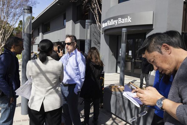 Thành viên FDIC Dedra Dorn (giữa bên trái) nói chuyện với những người xếp hàng bên ngoài trụ sở Silicon Valley Bank ở Santa Clara, California. - Sputnik Việt Nam
