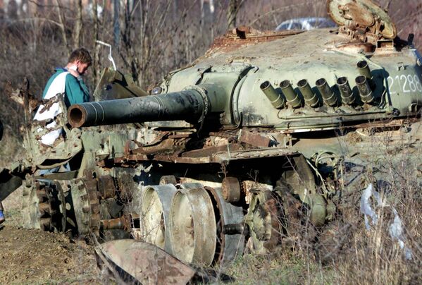 Một người Albania đi ngang qua chiếc xe tăng của quân đội Nam Tư bị phá hủy trong một cuộc không kích của NATO ở thành phố Klina phía tây Kosovo. - Sputnik Việt Nam
