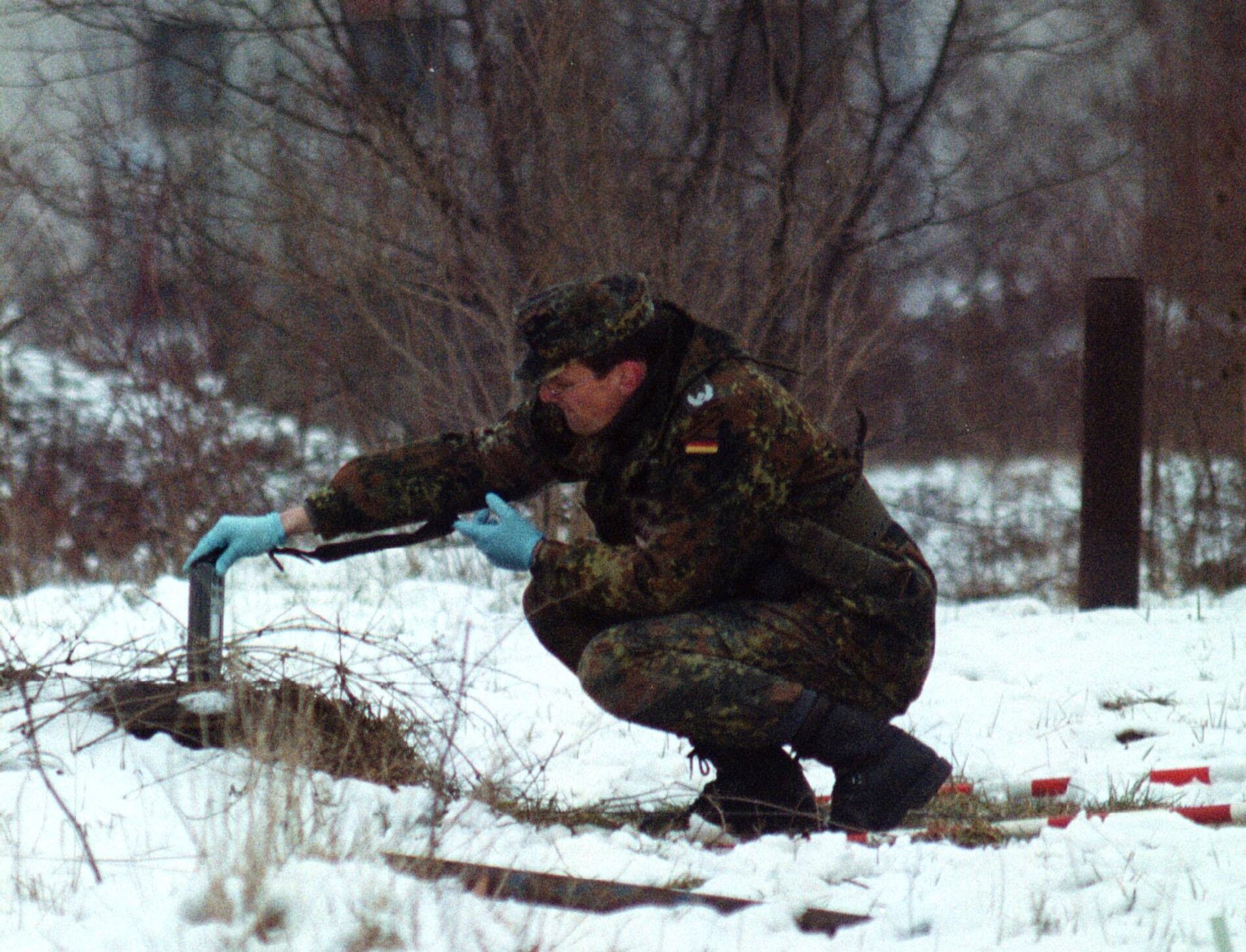 Một người lính NATO của Đức đo độ phóng xạ tại nơi từng là nhà máy của quân đội Serbia ở Bosnia, bị ném bom bằng đạn uranium nghèo 30 mm ở vùng ngoại ô Sarajevo của Hadzici, 2001 - Sputnik Việt Nam, 1920, 23.03.2023