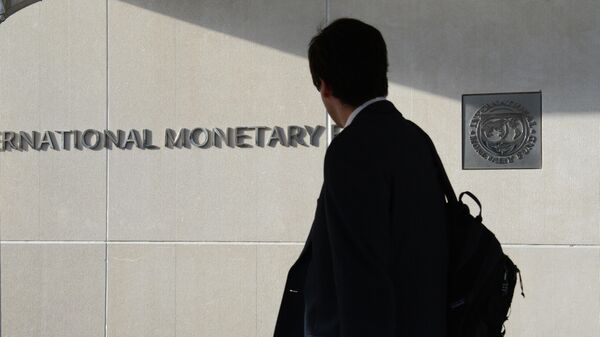 Một người đàn ông bên ngoài Quỹ Tiền tệ Quốc tế nhìn vào logo của IMF trên tường - Sputnik Việt Nam