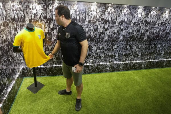 Người hâm mộ câu lạc bộ bóng đá Santos chạm vào một trong những chiếc áo thi đấu của cầu thủ bóng đá người Brazil Pele khi đến thăm lăng mộ của ông ở Santos, Brazil. - Sputnik Việt Nam