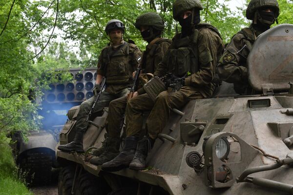 Binh sĩ trên xe bọc thép chở quân hộ tống hệ thống súng phun lửa hạng nặng TOS-1A Solntsepyok của Lực lượng vũ trang Nga trong khu vực diễn ra chiến dịch quân sự đặc biệt. - Sputnik Việt Nam