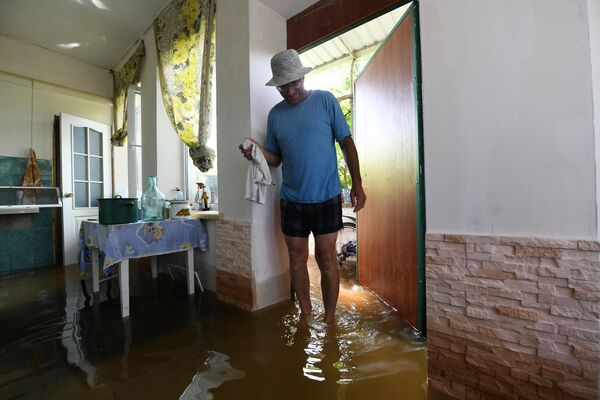 Người dân địa phương bên trong nhà trên khu đất vườn bị ngập nước ở Nova Kakhovka sau khi thủy điện Kakhovka bị phá hủy. - Sputnik Việt Nam