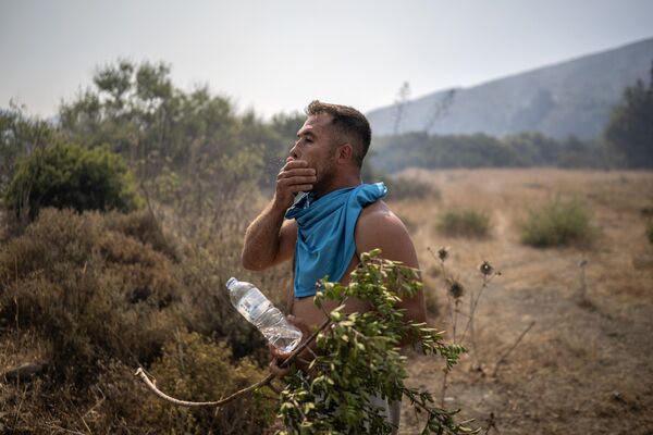 Người dân địa phương lấy nước làm mát mặt khi chứng kiến ​​đám cháy rừng bùng lên gần ngôi làng Vathy trên đảo Rhodes, miền nam Hy Lạp. - Sputnik Việt Nam