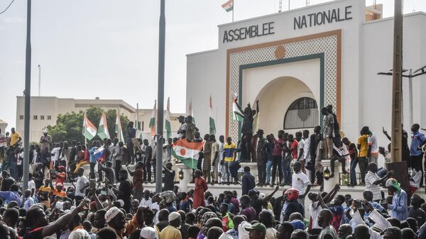 Những người ủng hộ vẫy cờ Nigeria trong cuộc tập hợp để ủng hộ chính quyền Nigeria trước tòa nhà Quốc hội ở Niamey - Sputnik Việt Nam