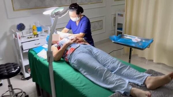 Nữ lao công T.T.T của thẩm mỹ viện Kangzin đang phẫu thuật căng da mặt cho khách. - Sputnik Việt Nam