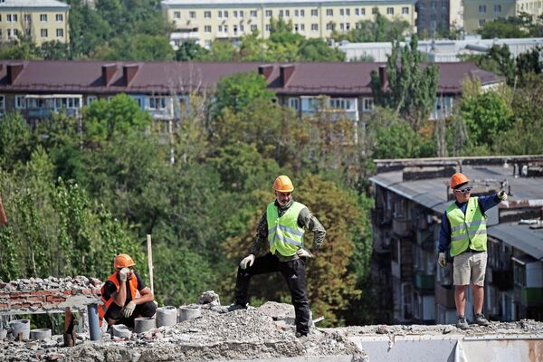 Công nhân tháo dỡ các tầng trên cùng của tòa nhà bị hư hại trên Đại lộ Lenin ở Mariupol. - Sputnik Việt Nam