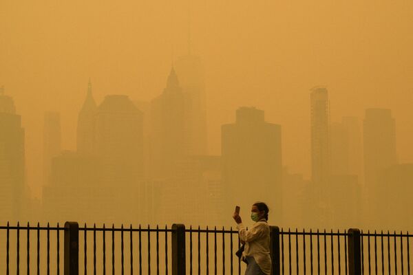 Cô gái đeo khẩu trang chụp ảnh sương mù tại thành phố New York do cháy rừng ở Canada gây ra. - Sputnik Việt Nam