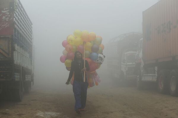 Người bán hàng Pakistan giao bóng bay trên phố giữa sương mù dày đặc ở Lahore. - Sputnik Việt Nam