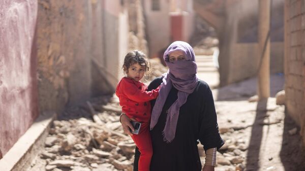 Một người phụ nữ và bé gái đứng bên ngoài ngôi nhà của họ sau trận động đất ở làng Moulay Brahim, Morocco - Sputnik Việt Nam