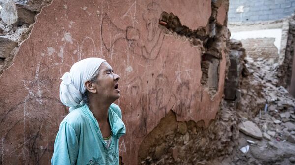 Một người phụ nữ đứng trước ngôi nhà bị hư hại do động đất ở thành phố cổ Marrakech - Sputnik Việt Nam