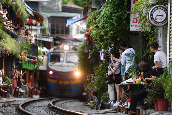 Du khách chụp ảnh đoàn tàu đi qua khu phố cổ ở trung tâm Hà Nội - Sputnik Việt Nam
