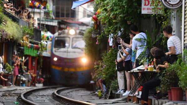 Du khách chụp ảnh đoàn tàu đi qua khu phố cổ ở trung tâm Hà Nội - Sputnik Việt Nam