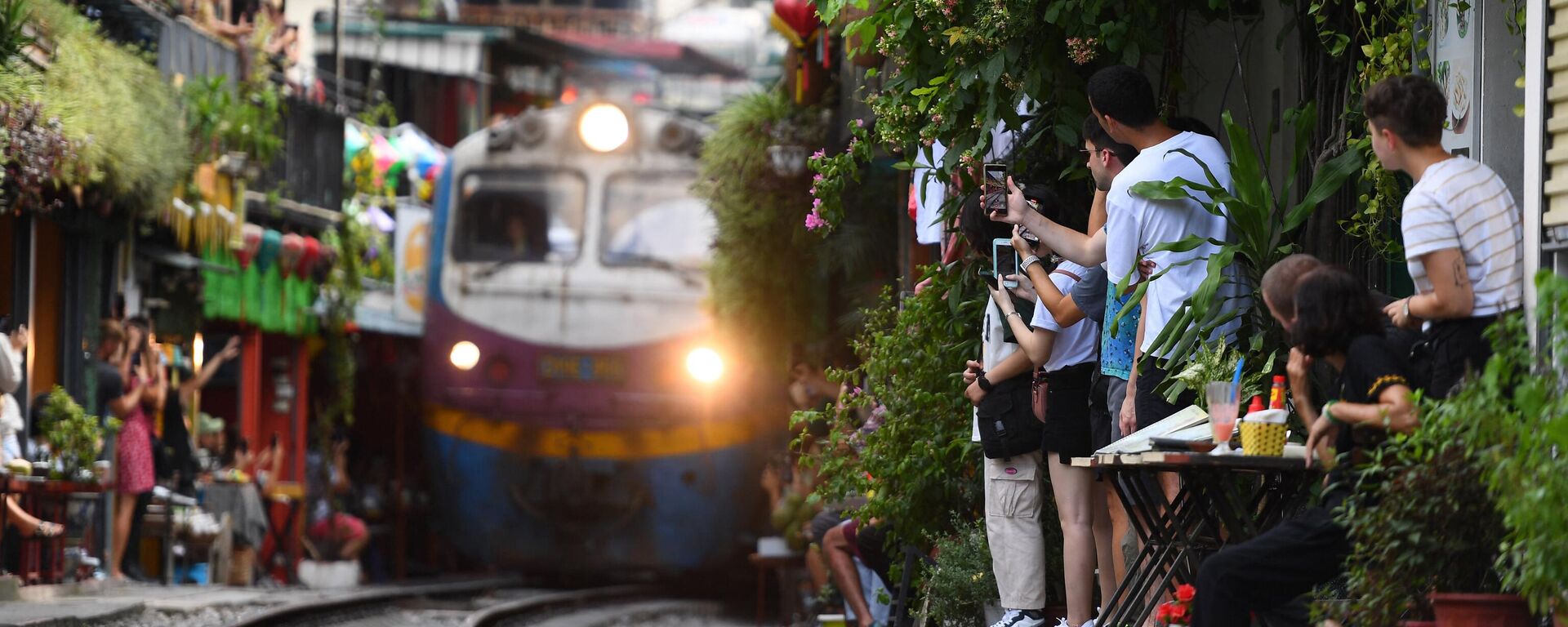 Du khách chụp ảnh đoàn tàu đi qua khu phố cổ ở trung tâm Hà Nội - Sputnik Việt Nam, 1920, 27.09.2023