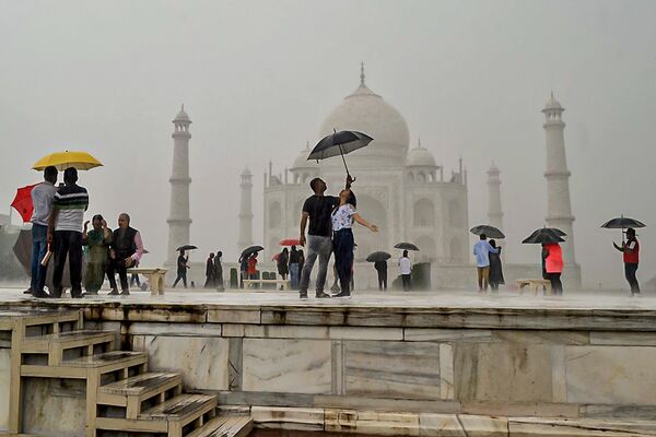 Khách du lịch cầm ô và tạo dáng chụp ảnh khi đến thăm Taj Mahal trong trận mưa như trút nước ở Agra - Sputnik Việt Nam
