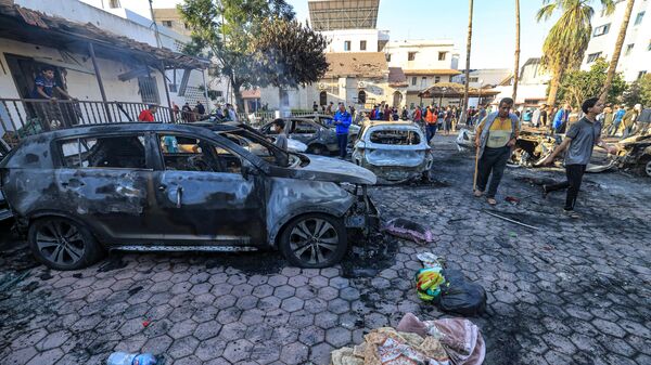 Người dân tụ tập bên những phương tiện bị phá hủy tại địa điểm bệnh viện ở trung tâm Gaza vào ngày 18 tháng 10 năm 2023 sau vụ nổ qua đêm ở đó. - Sputnik Việt Nam