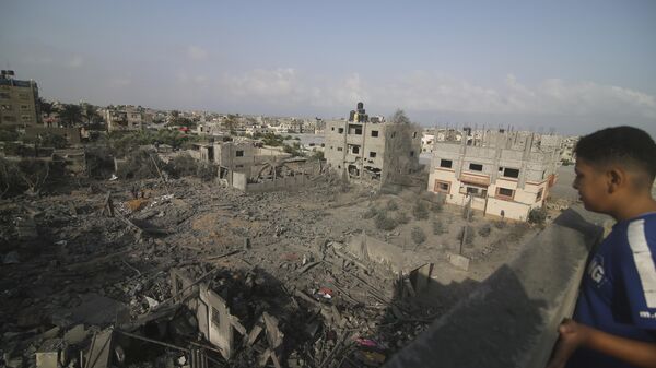 Cậu bé nhìn những tòa nhà bị phá hủy do cuộc ném bom của Israel vào Dải Gaza ở Rafah - Sputnik Việt Nam