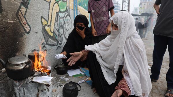 Một người phụ nữ đốt giấy để làm nóng nước trà ở Rafah, phía nam Gaza - Sputnik Việt Nam