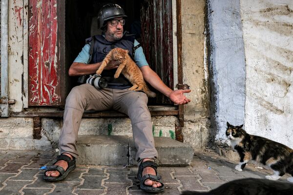 Nhiếp ảnh gia AFP Mohammed Abed ngồi bên ngoài ngôi nhà ở Rafah, phía nam Dải Gaza, xung quanh là những chú mèo - Sputnik Việt Nam