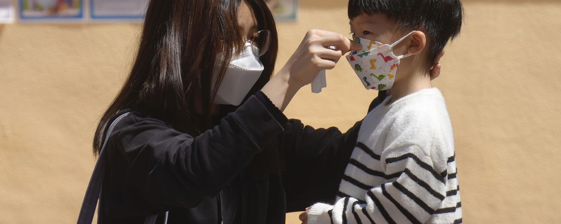Женщина поправляет маску для лица ребенку в Гонконге, Китай - Sputnik Việt Nam, 1920, 04.12.2023
