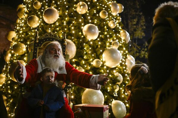Người đàn ông hóa trang thành ông già Noel mời trẻ em chụp ảnh cùng trước cây thông Noel ở Sofia, Bulgaria - Sputnik Việt Nam